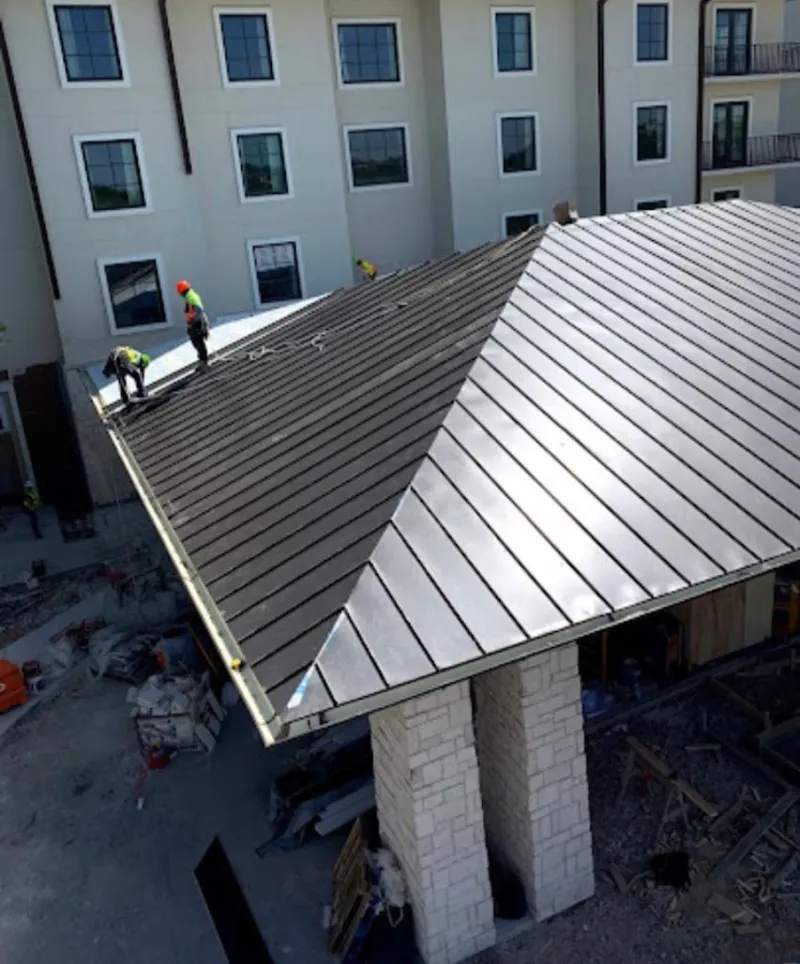 Crew installing standing seam metal roof panels on a commercial project in Lewisburg